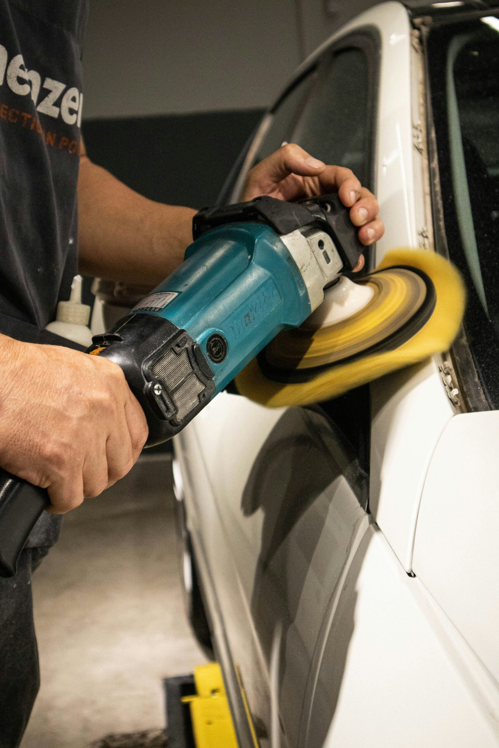 a man sanding a car with a power sander